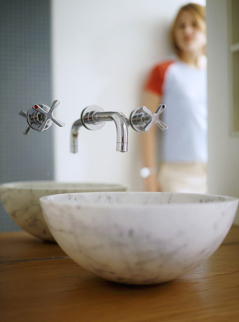 Waschschüssel aus Marmor und Wandarmatur vor Spiegel im Designerstil