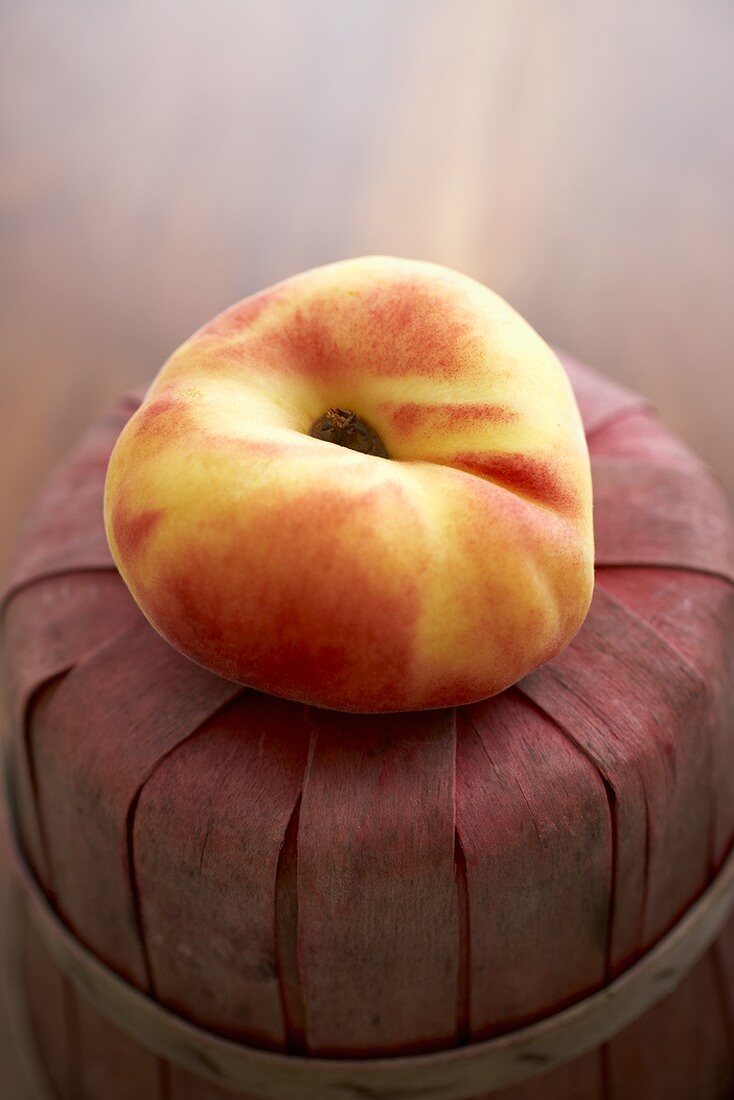 A Single Organic Saucer Peach on a Basket