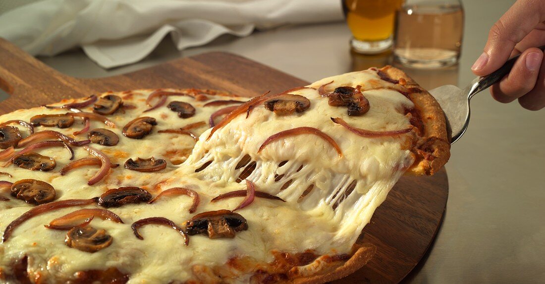 Stück aus Champignon-Käse-Pizza herausheben