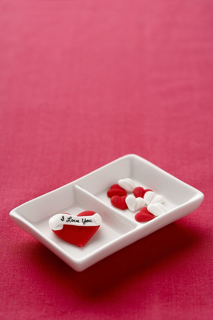 Herzförmige Bonbons mit Aufschrift in zweigeteilter Schale