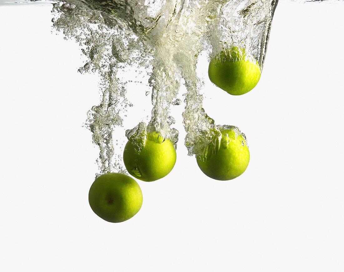 Green Apples Splashing into Water
