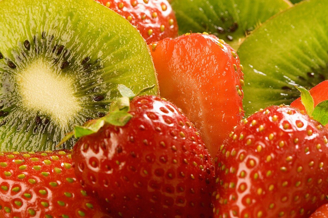 Mehrere frische Erdbeeren und halbierte Kiwis