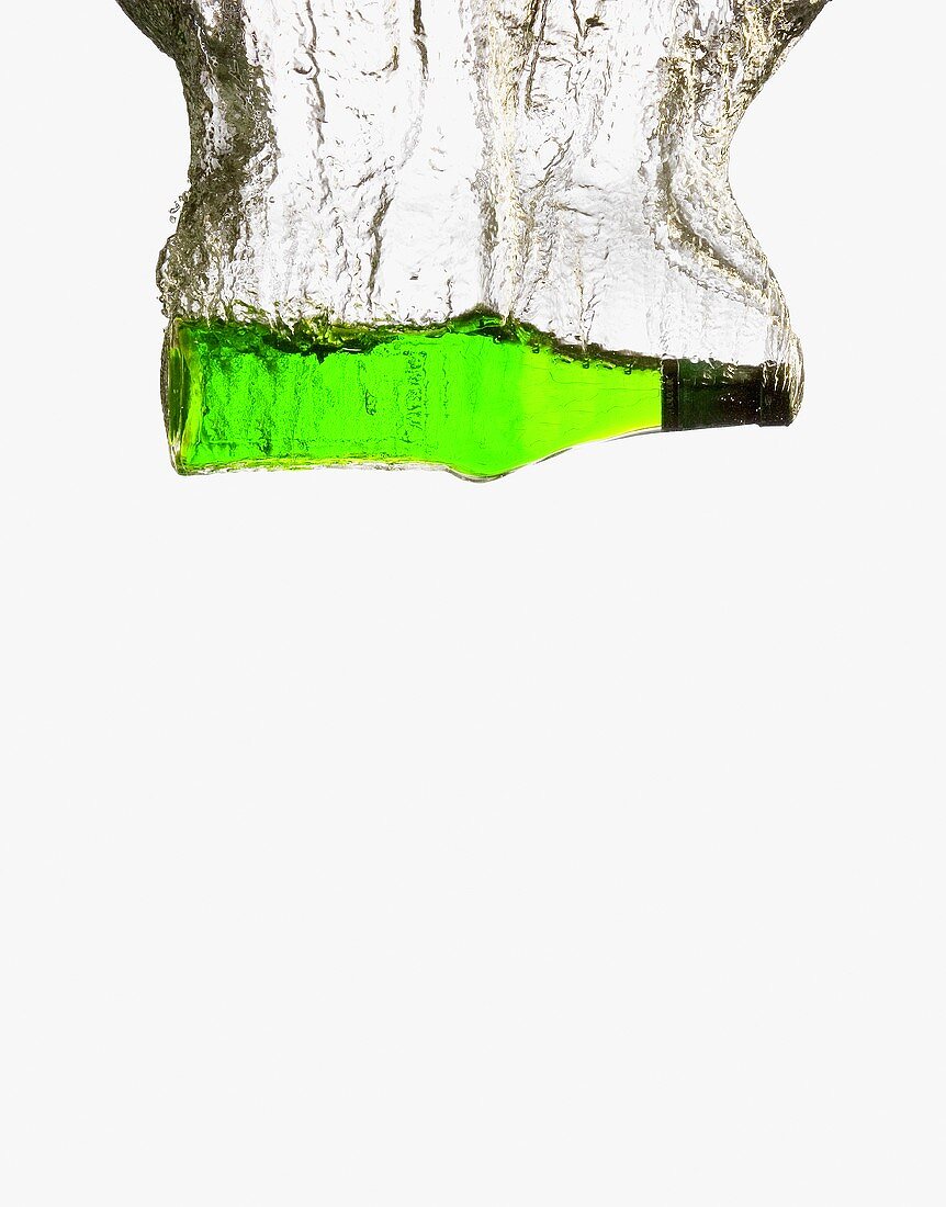 Eine Flaschen mit grünem Melonenlikör versinkt im Wasser