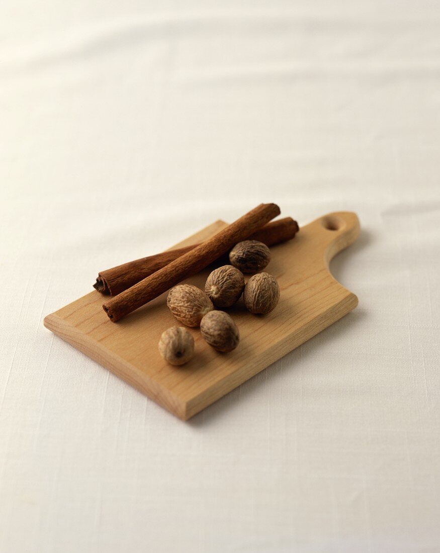 Nutmeg and Cinnamon Sticks on a Wooden Board