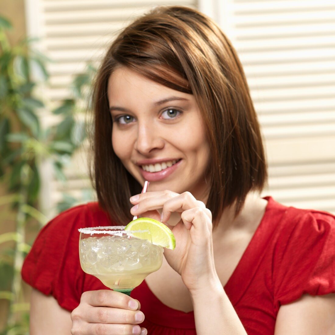 Junge Frau hält Glas Margarita mit Salzrand und Strohhalm