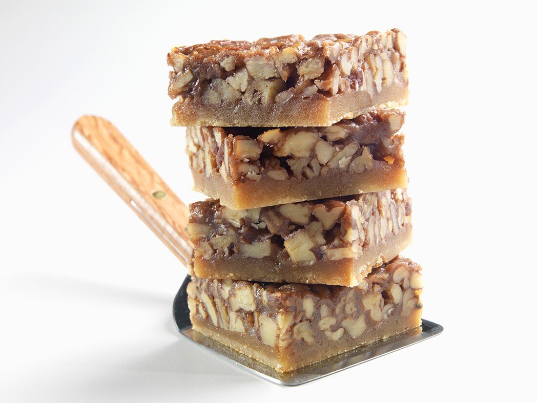Stack of Four Honey Pecan Squares on a Spatula, White Background