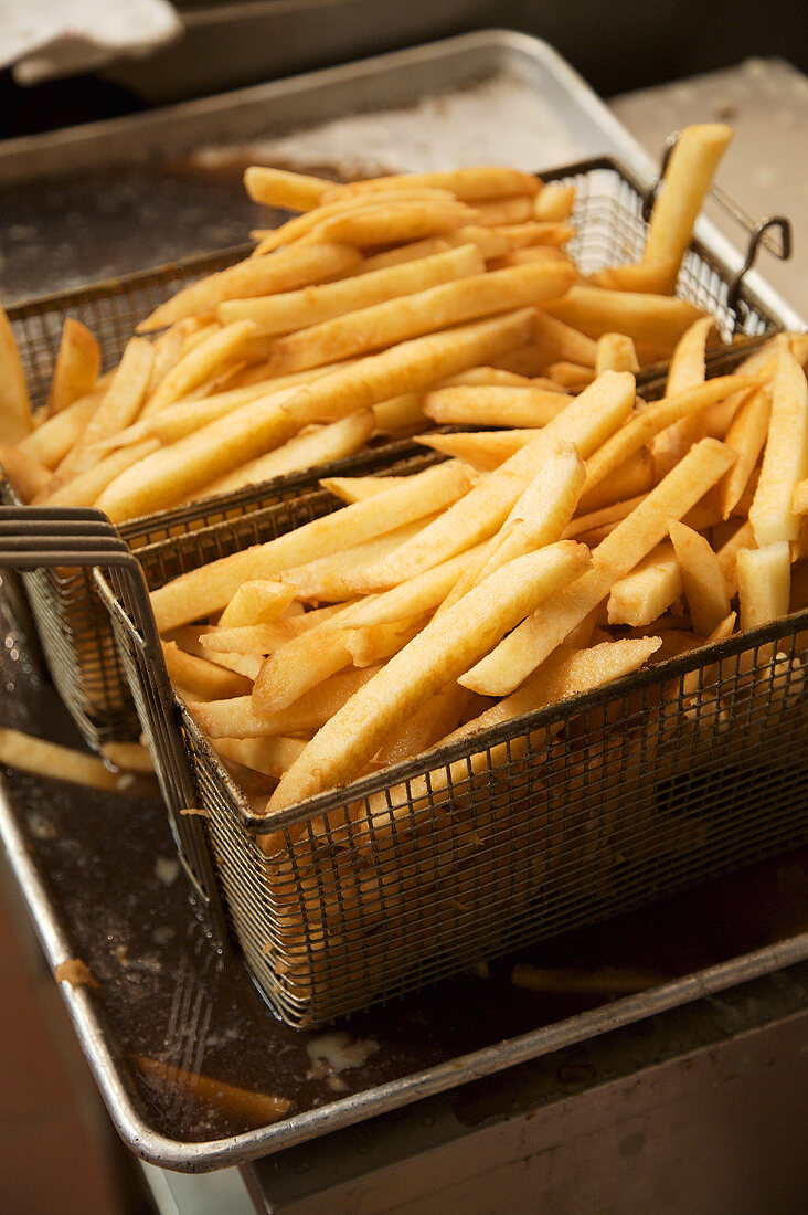 French Fries in Deep Fryer Baskets Over Frying Oil