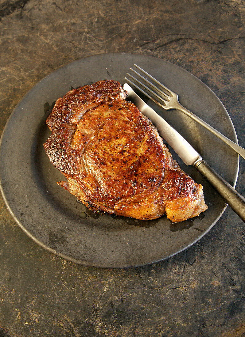 Rib Eye Steak on a Plate with a Fork and Knife