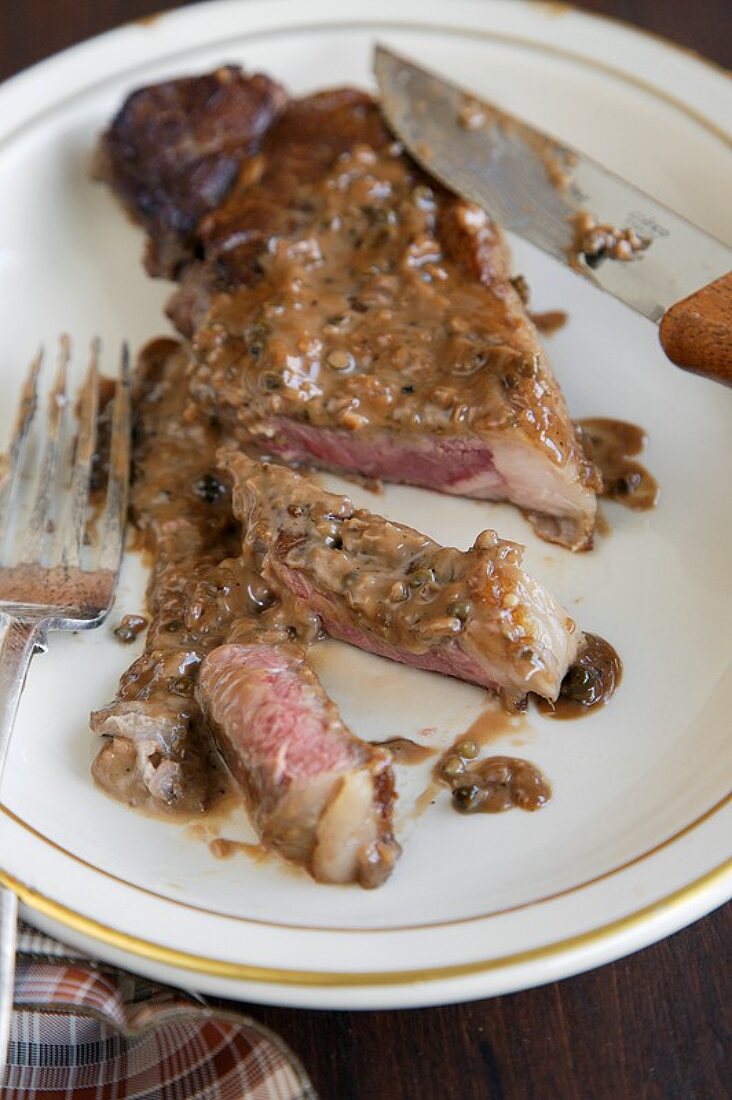 Strip Steak mit Pfeffersauce, angeschnitten, auf Teller