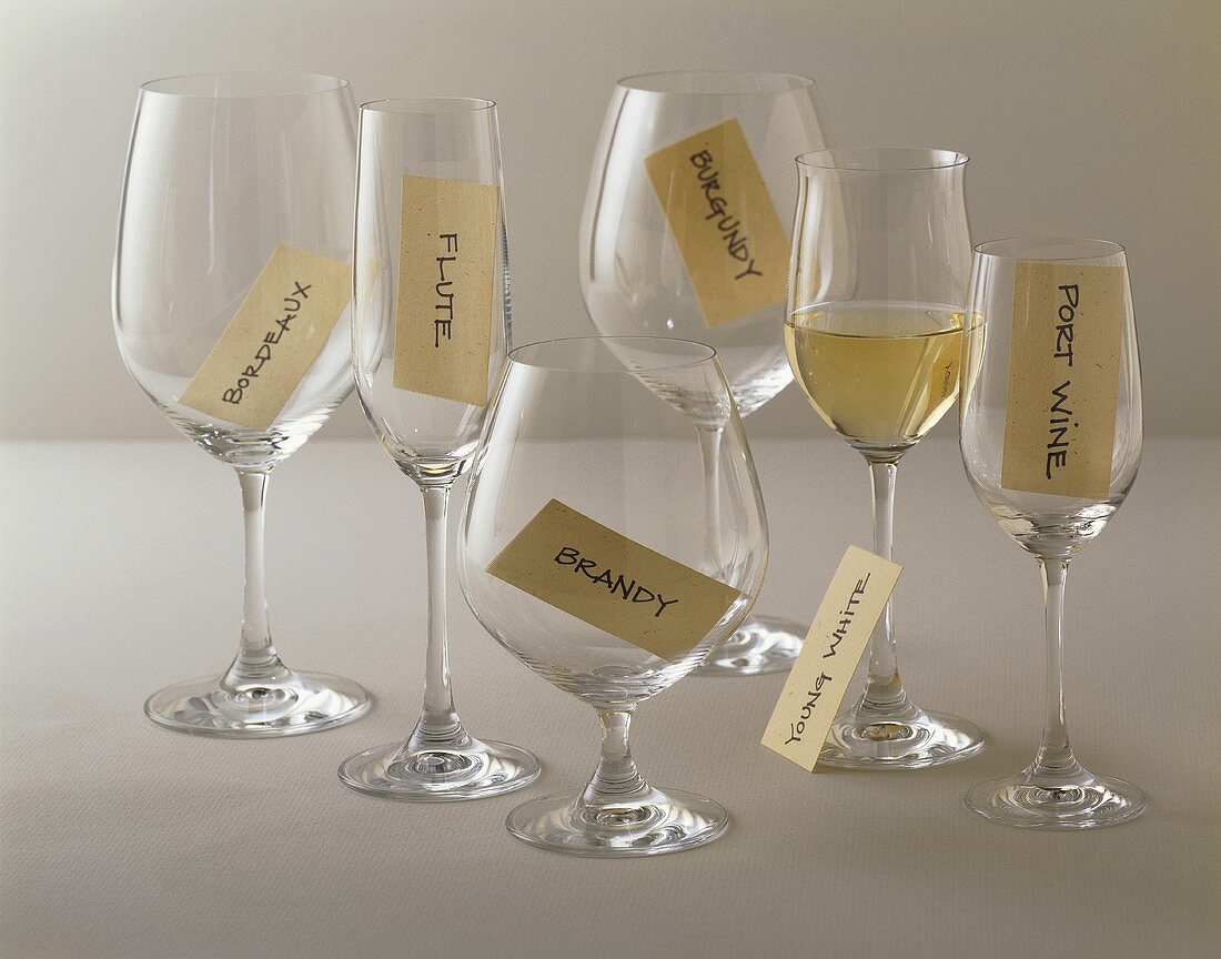 Leere Weingläser mit Etiketten und Glas Weißwein