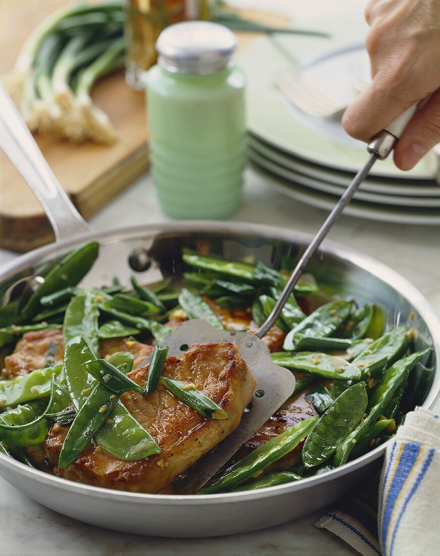 Boneless Pork Chops with Snow Peas in a Skillet, Removing Pork Chop with Spatula