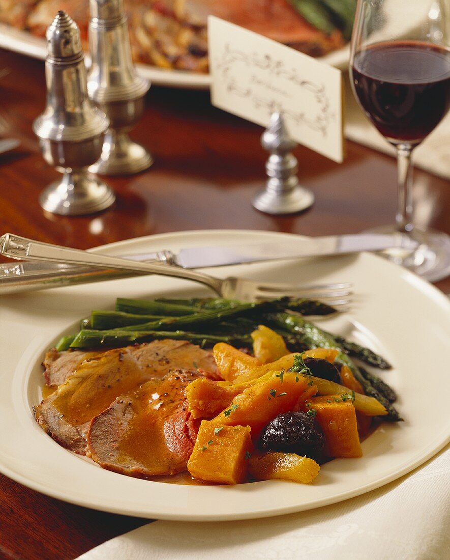 Slices of Roasted Lamb with Tzimmes and Asparagus, Red Wine, Dinner Table