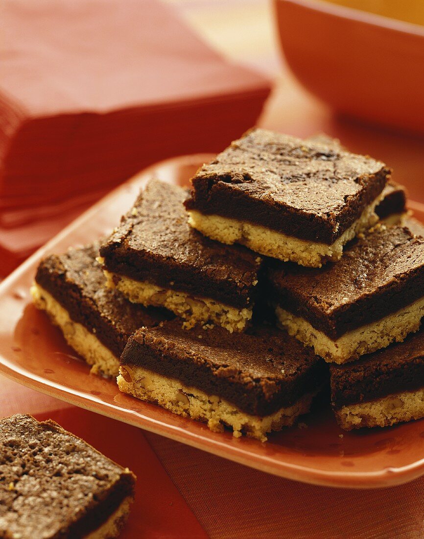 Brownie Pecan Shortbread Bars Stacked on an Orange Plate