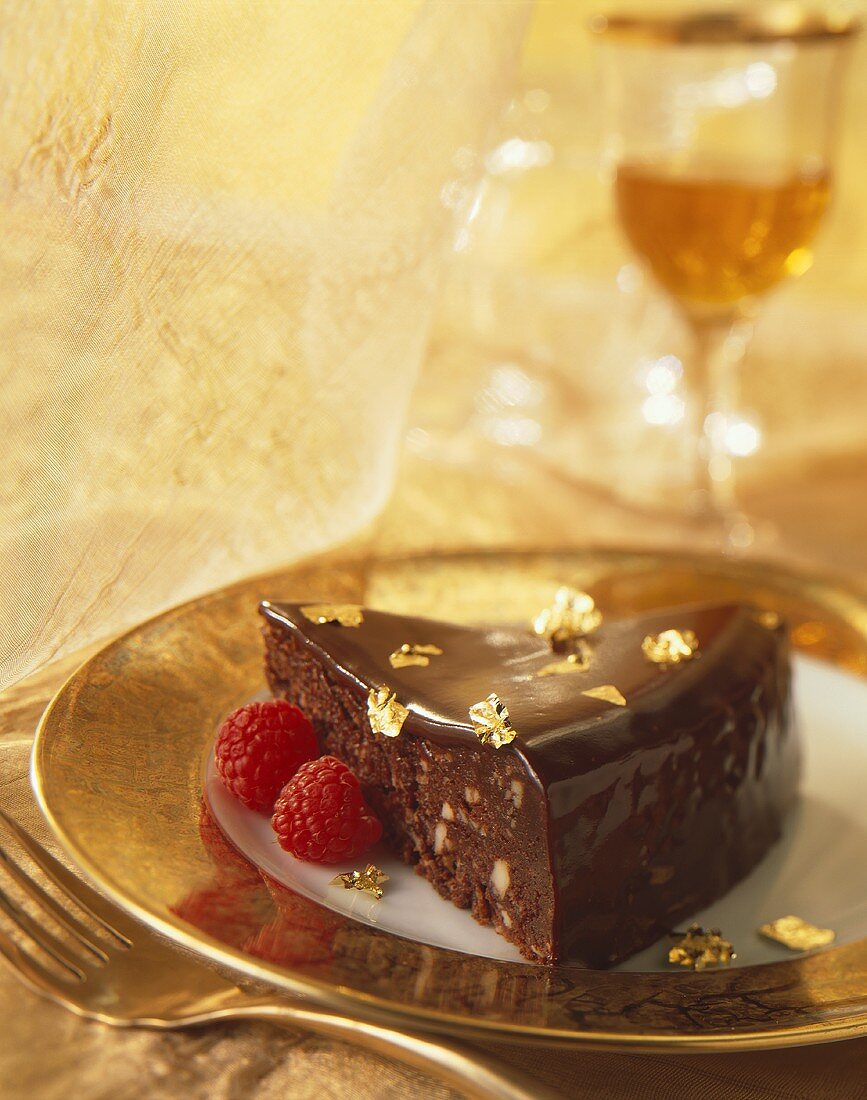 Stück Schokoladentorte, mit Gold und Himbeeren dekoriert