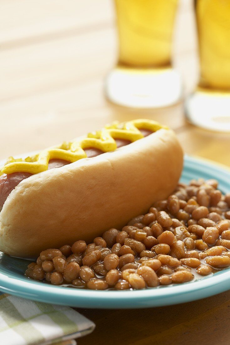 Hot Dog mit Senf und Baked Beans auf einem Teller