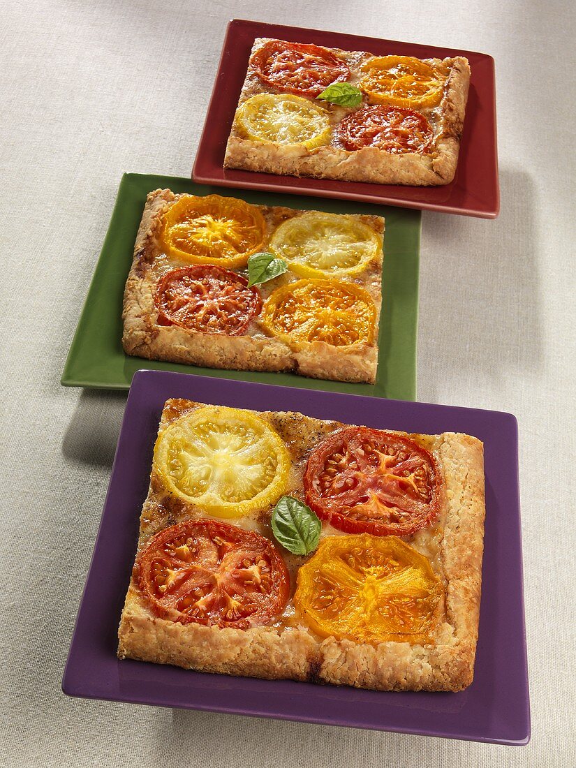 Drei Stücke Galette mit Tomaten auf Tellern
