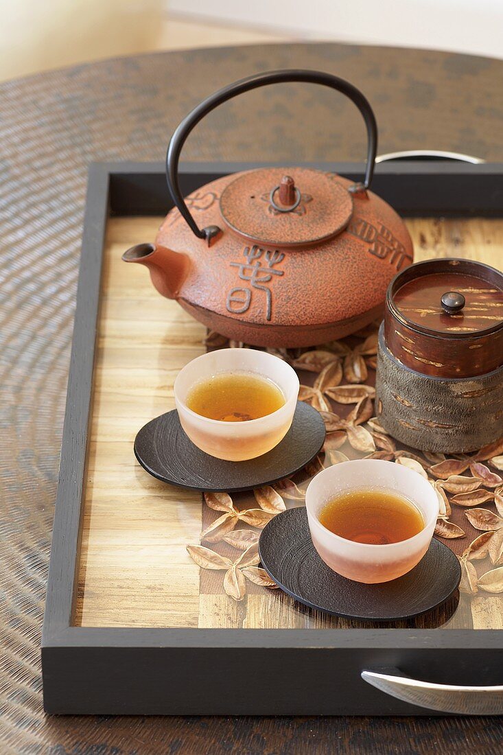 Asian teapot and two bowls of tea on tray