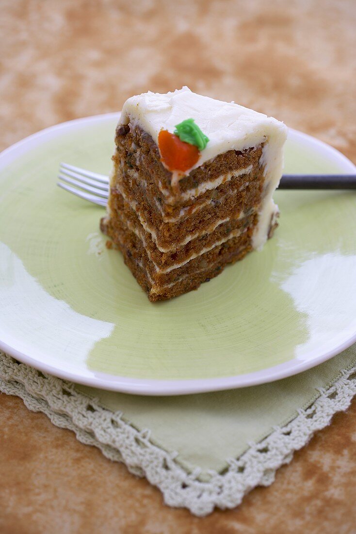 Ein Stück Karotten-Schichttorte mit Zuckerguss auf Teller