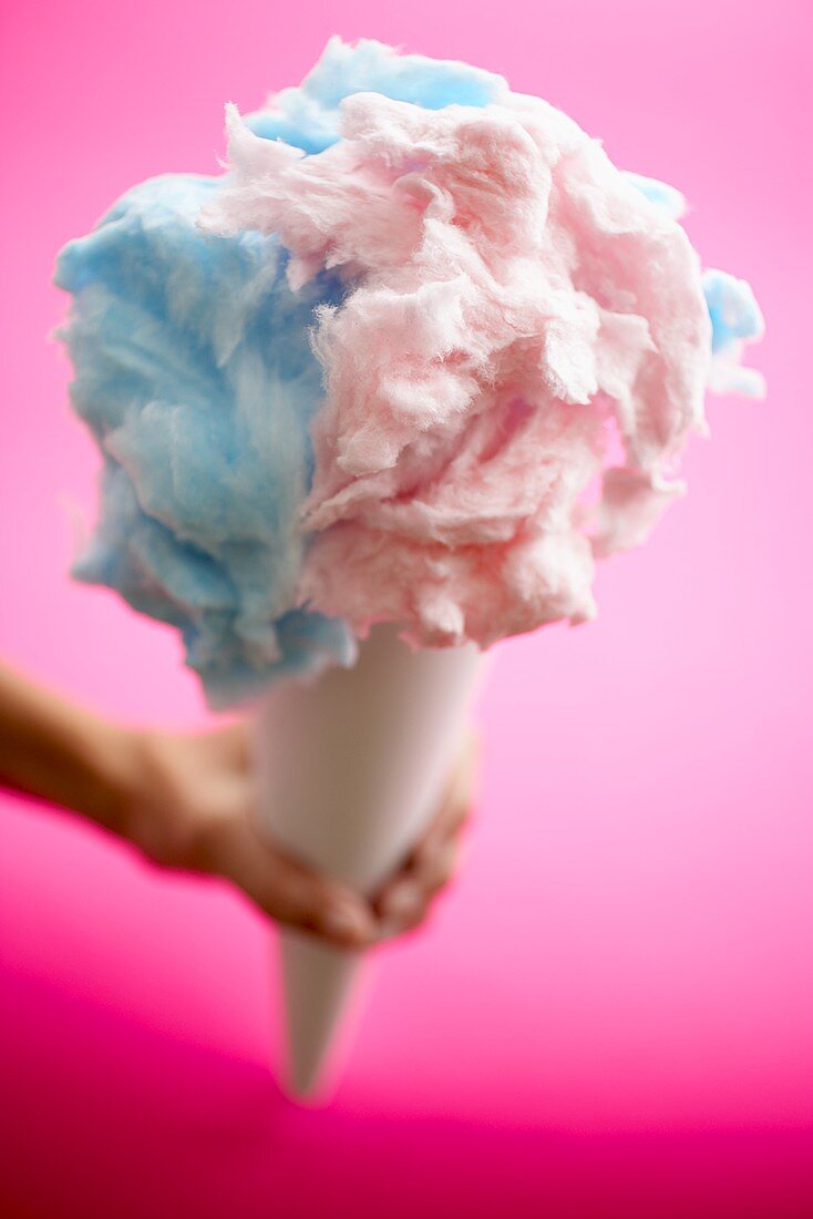 Hand hält Tüte mit blauer & rosafarbener Zuckerwatte