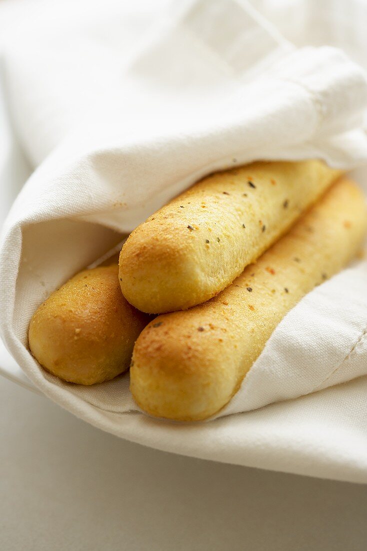 Three Bread Sticks Wrapped in White Linens