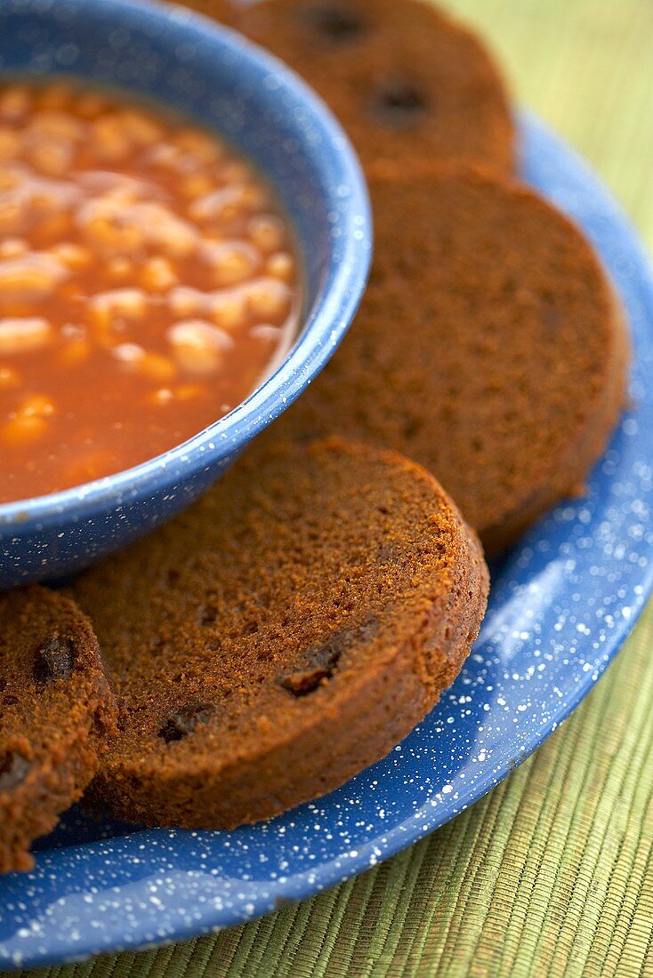 Slices of Boston Brown Bread with a Bowl of Baked Beans; Close Up