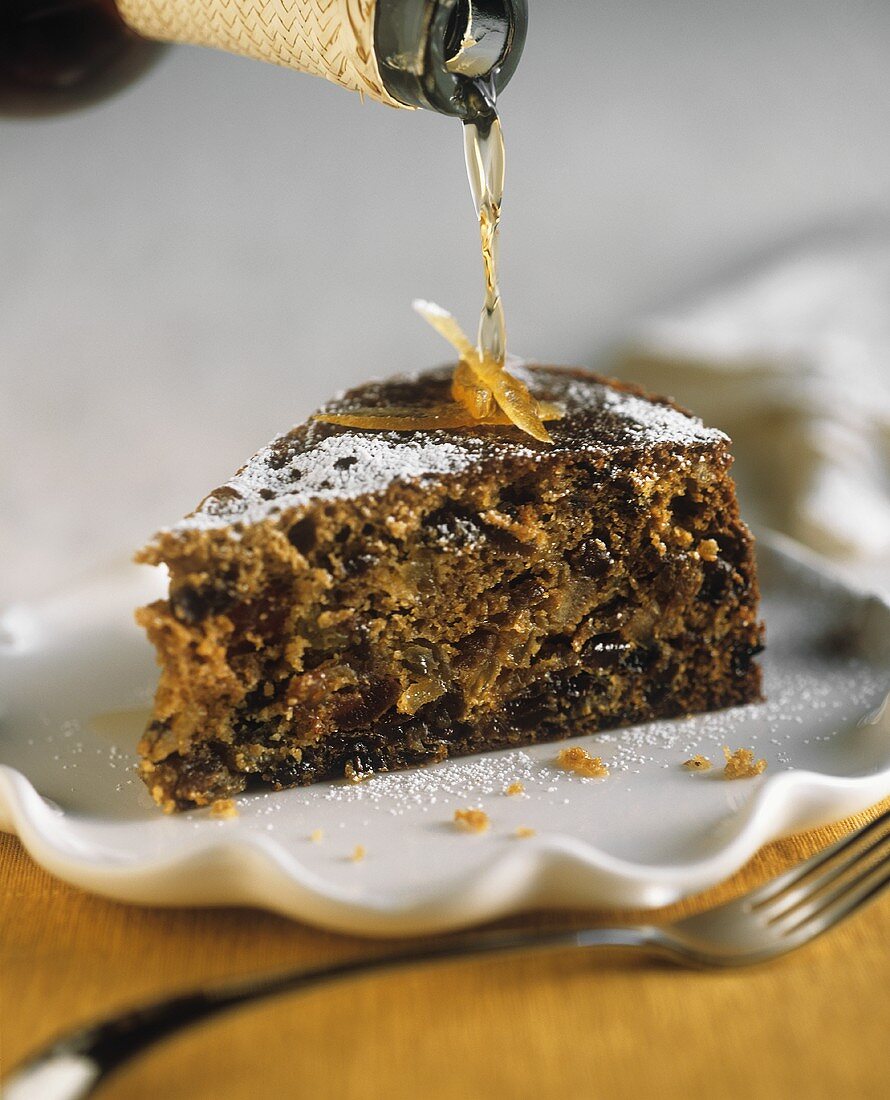 Stück Früchtekuchen mit Brandy begiessen