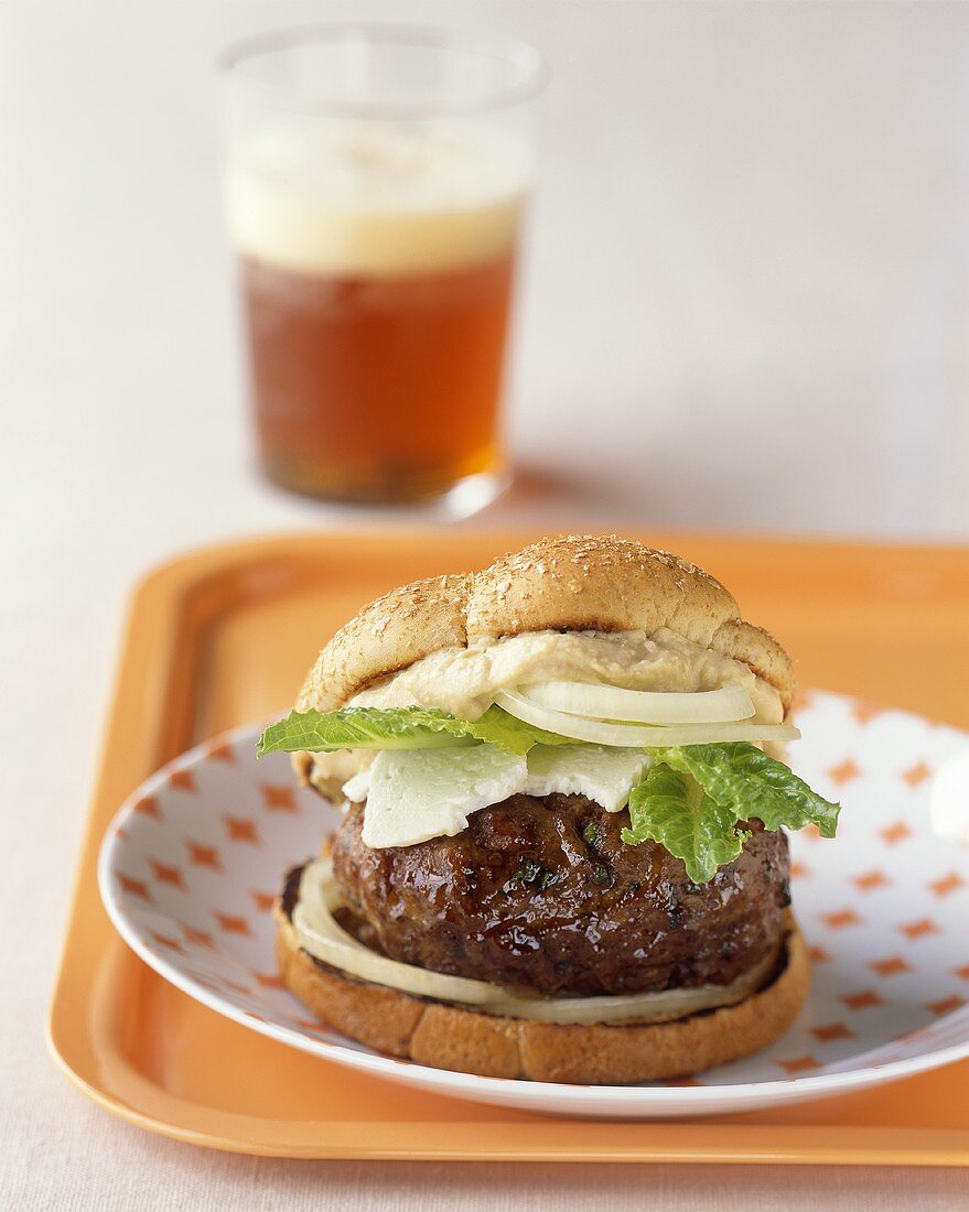 Cheeseburger mit Zwiebeln und Salatblatt, Glas Bier