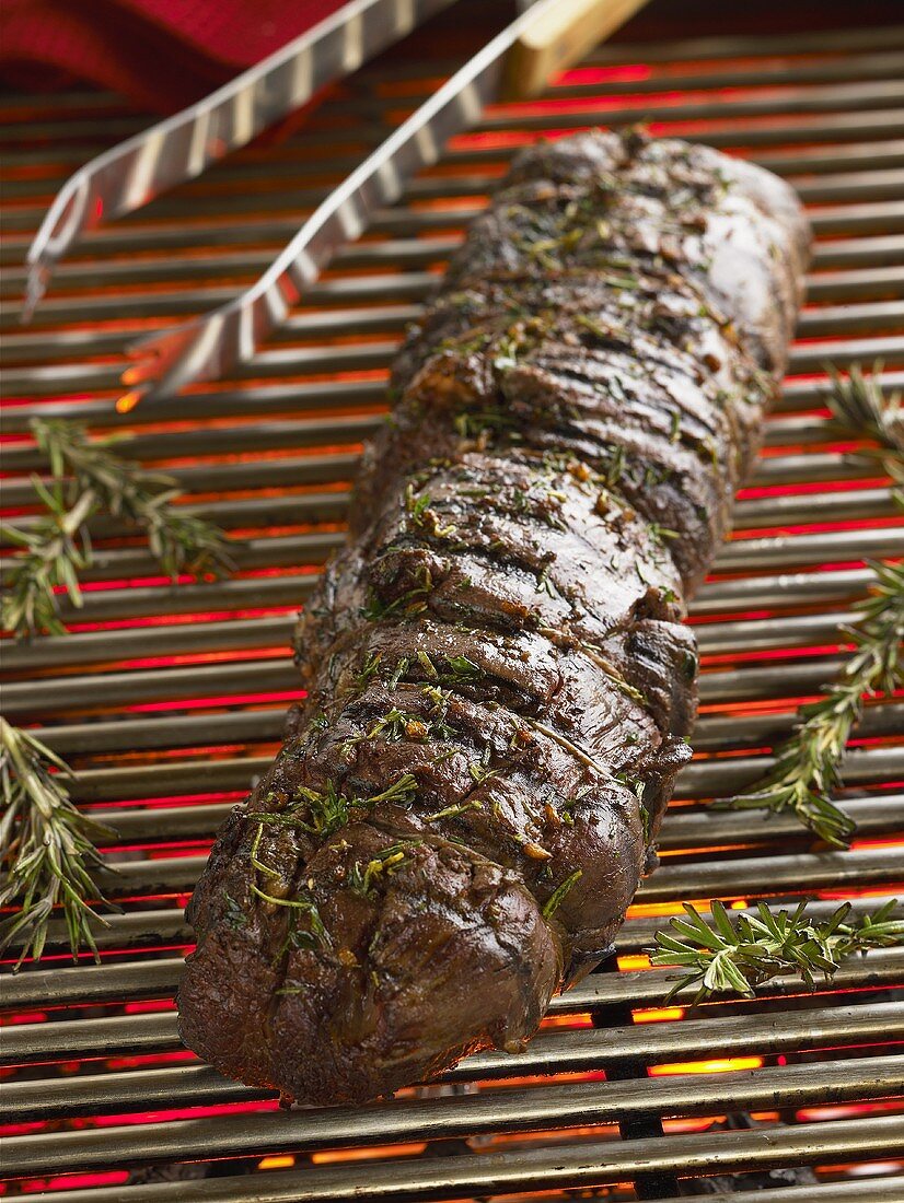 Mariniertes Rinderfilet mit Rosmarin auf einem Holzkohlegrill