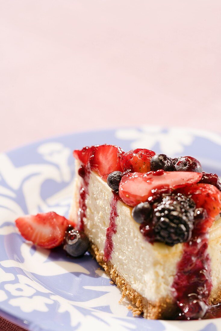 Ein Stück Käsekuchen mit marinierten Beeren auf einem Teller