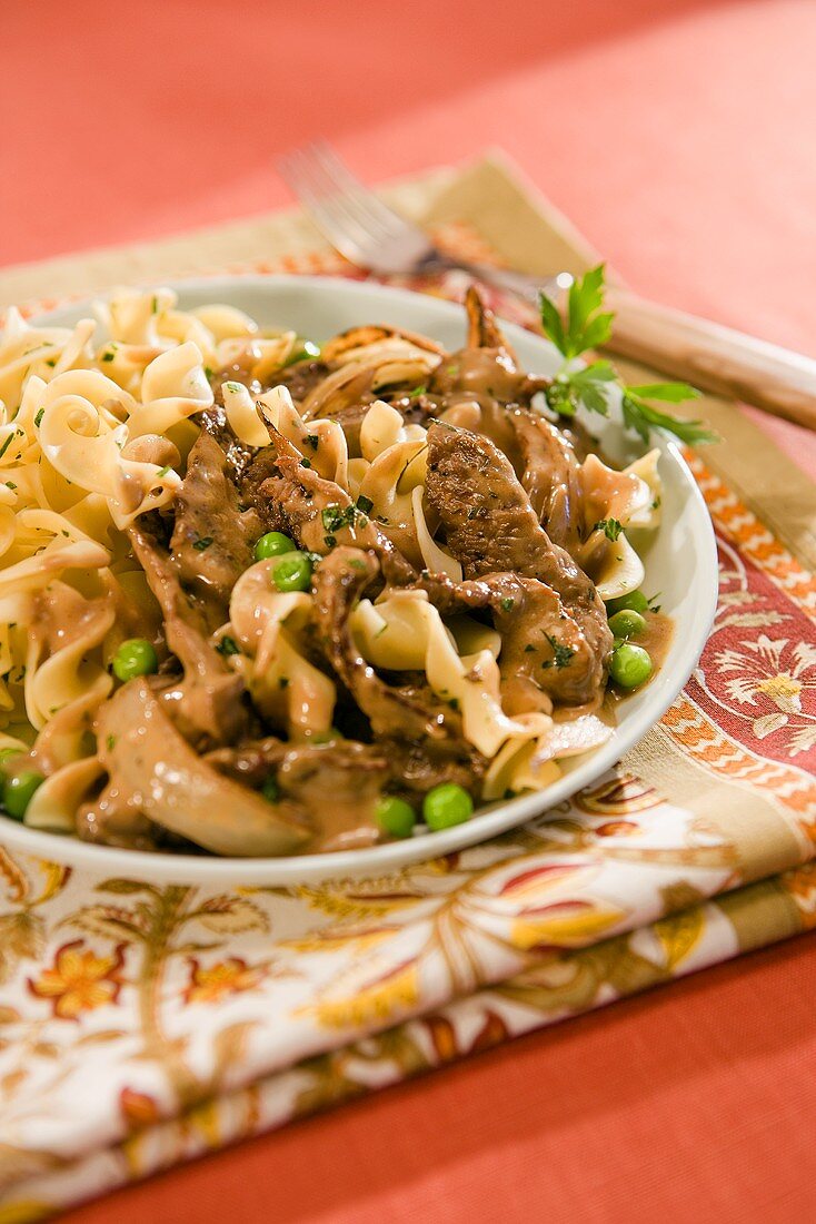 Ein Teller mit Boeuf Stroganoff mit Erbsen und Nudeln