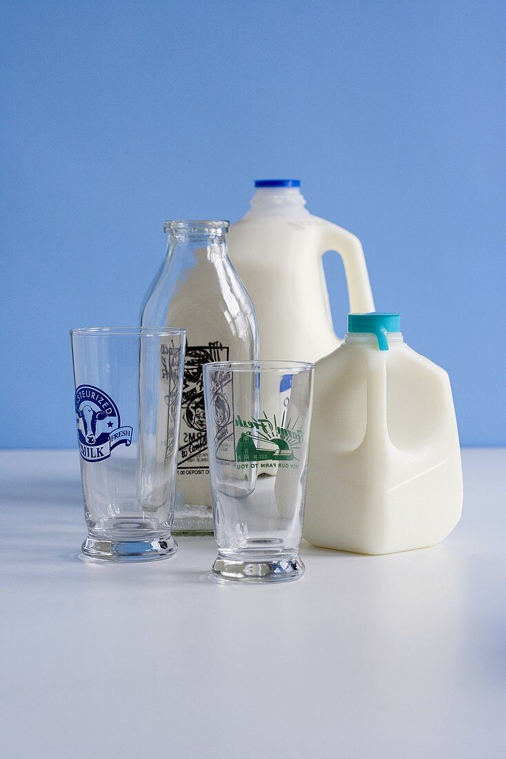 Zwei Kunststoffmilchflaschen, Milchgläser und eine leere Glasflasche
