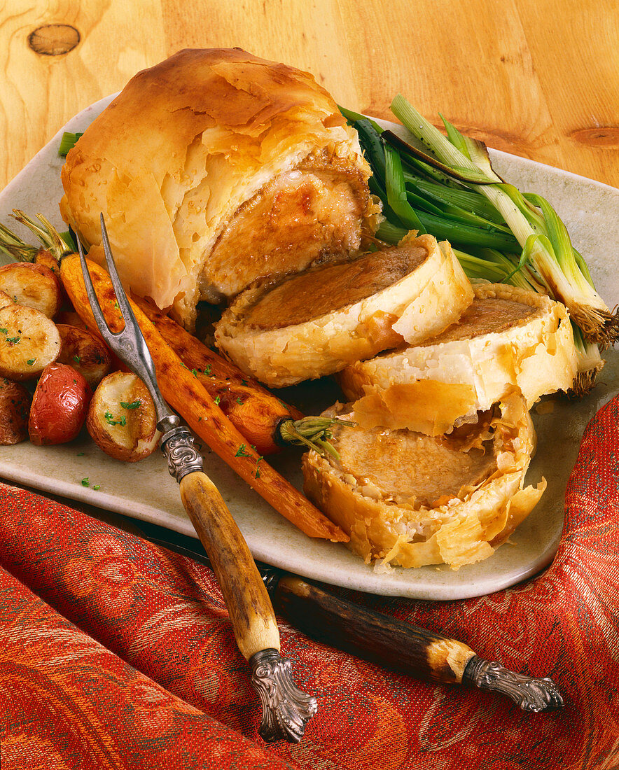 Roast pork in Phyllo Sliced on a Platter with Roast Vegetables