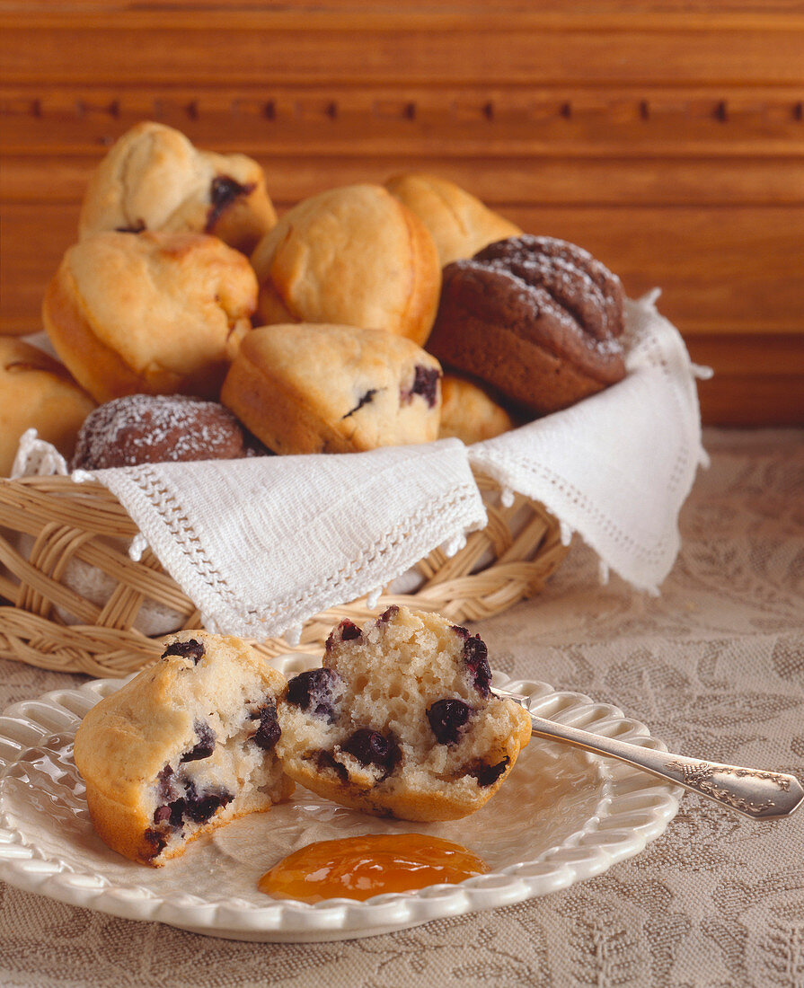 Blueberry Muffin Halved on a Plate; Basket of Assorted Muffins