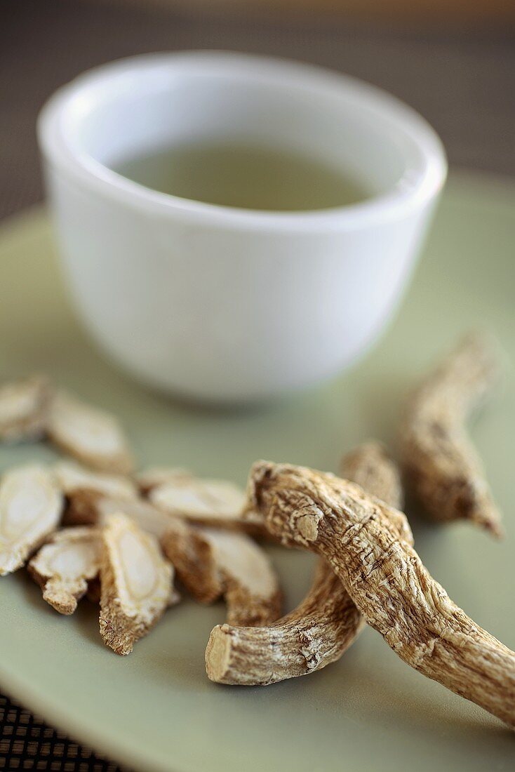 Dried Ginseng Root on a Plate with a Cup of Ginseng Tea