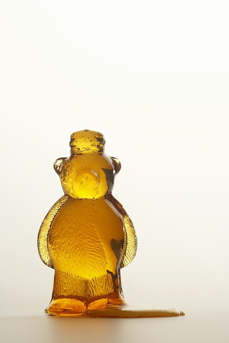 Honey Spilling From an Opened Honey Bear, White Background