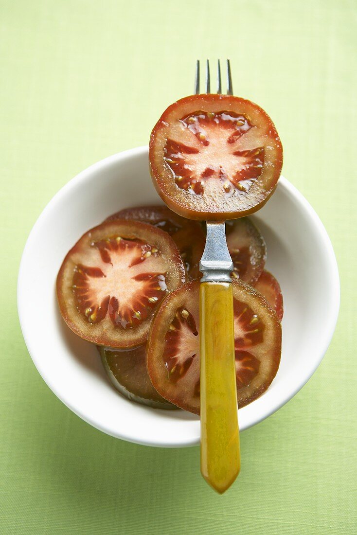 Slices of Rosso Bruno Tomatoes in a Bowl, One on a Fork