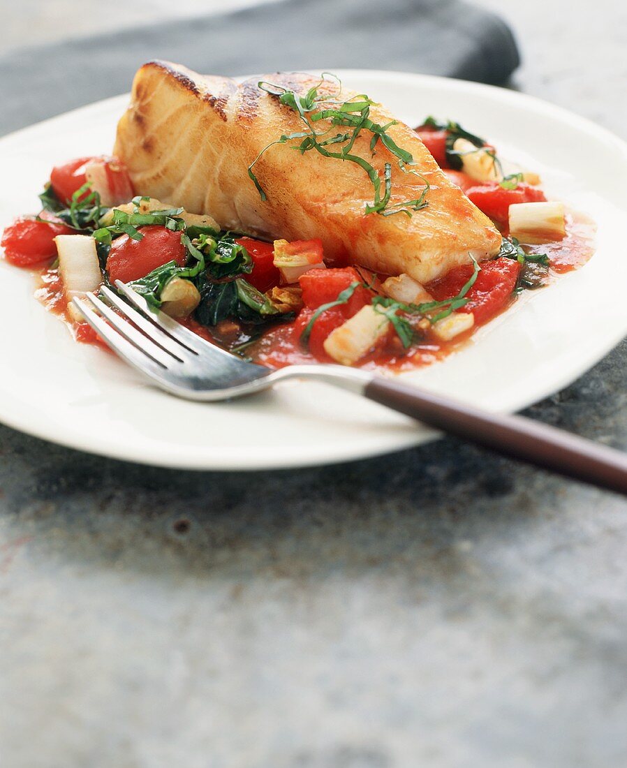 Salmon Fillet on Tomatoes with Basil Garnish; On a Plate with a Fork