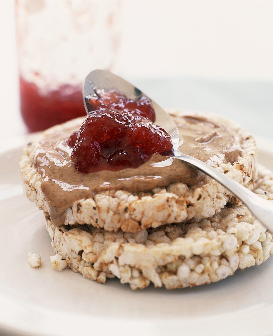 Spooning Jelly Over Peanut Butter on Rice Cakes