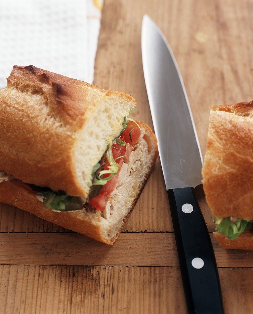 Sandwich mit Pute, Tomate und Blattsalat, mit Messer durchgeschnitten