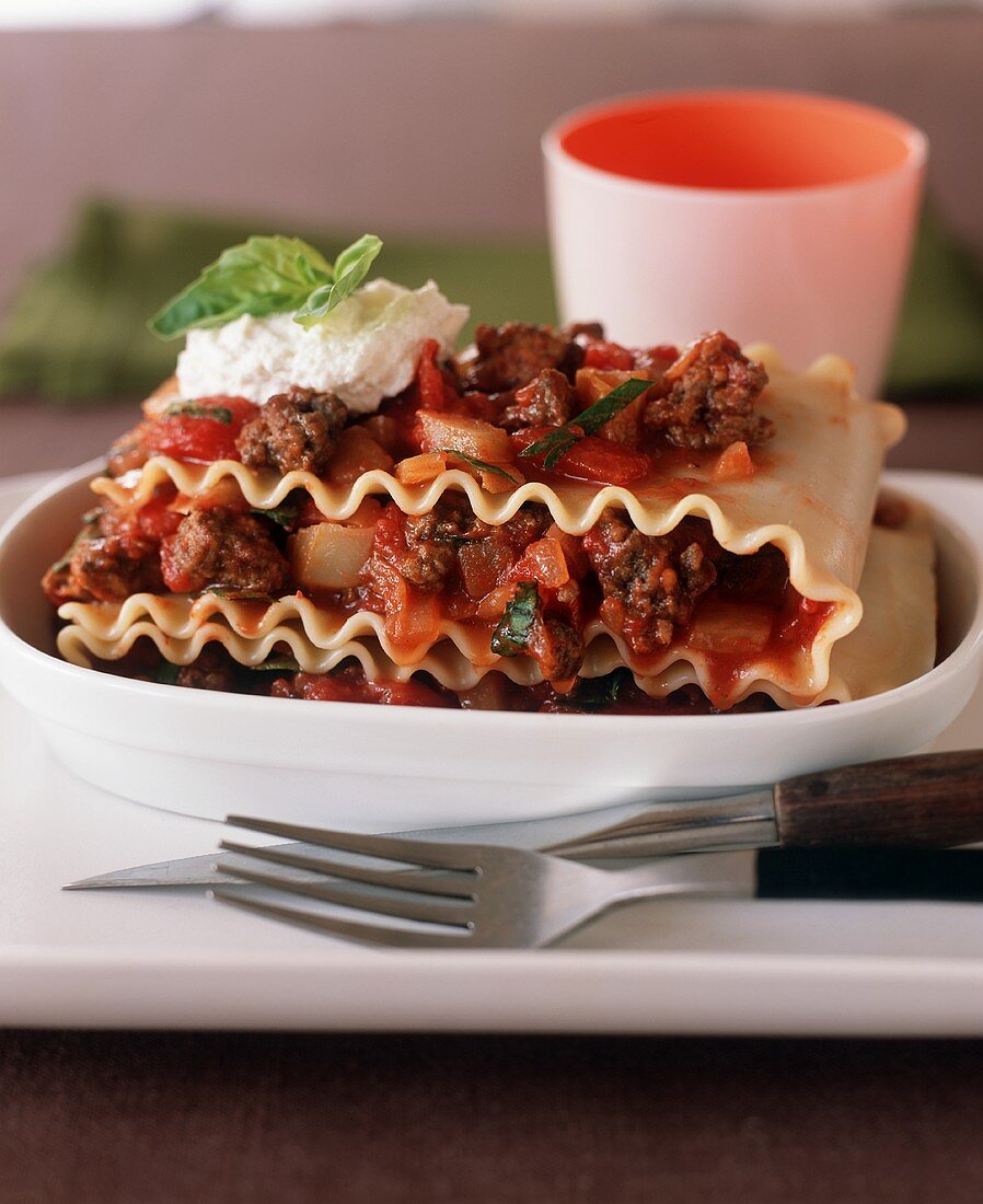 Serving of Ground Beef Lasagna in an Oval Dish; Fork and Knife