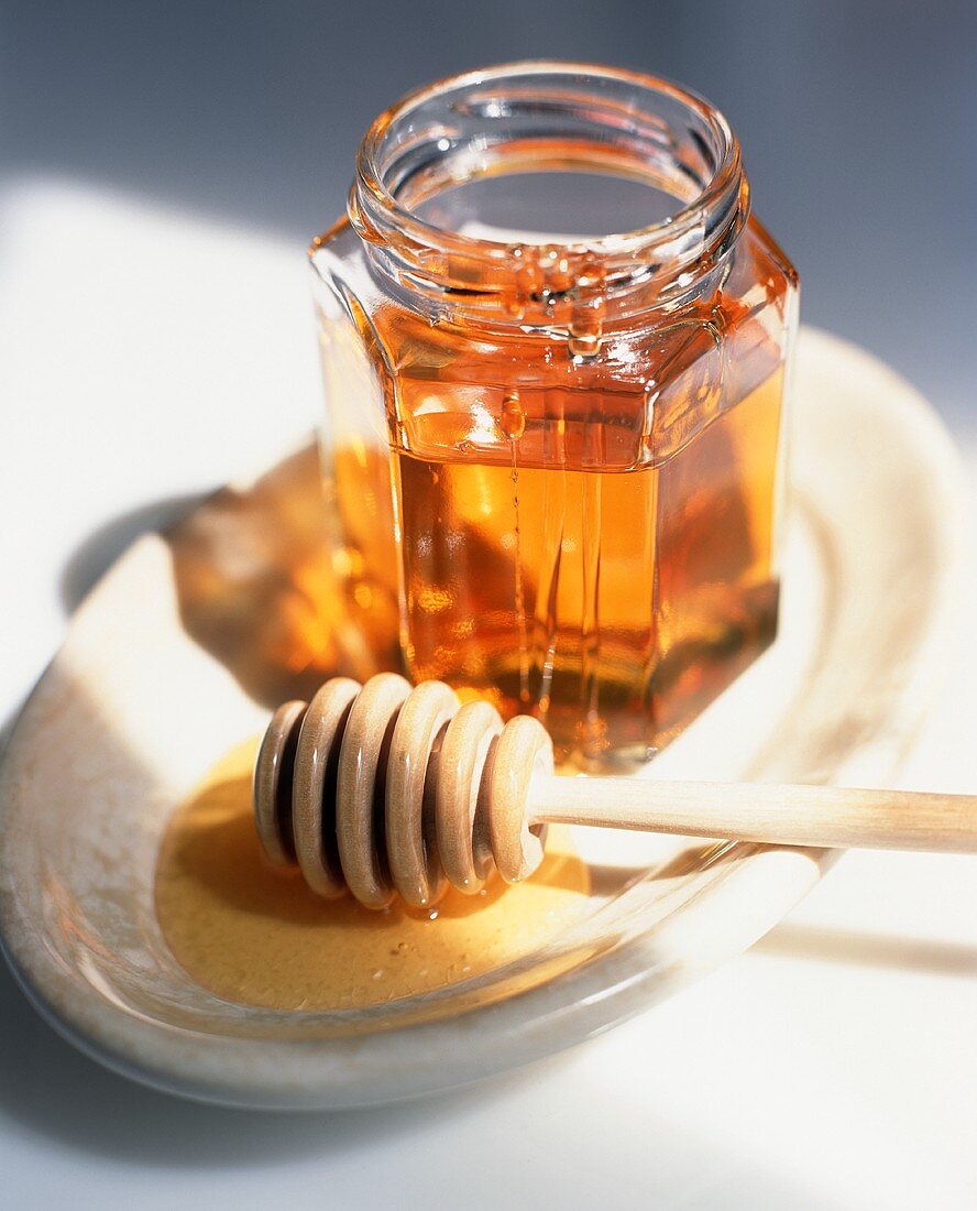 Honey Dipper and Opened Jar of Honey on a Dish