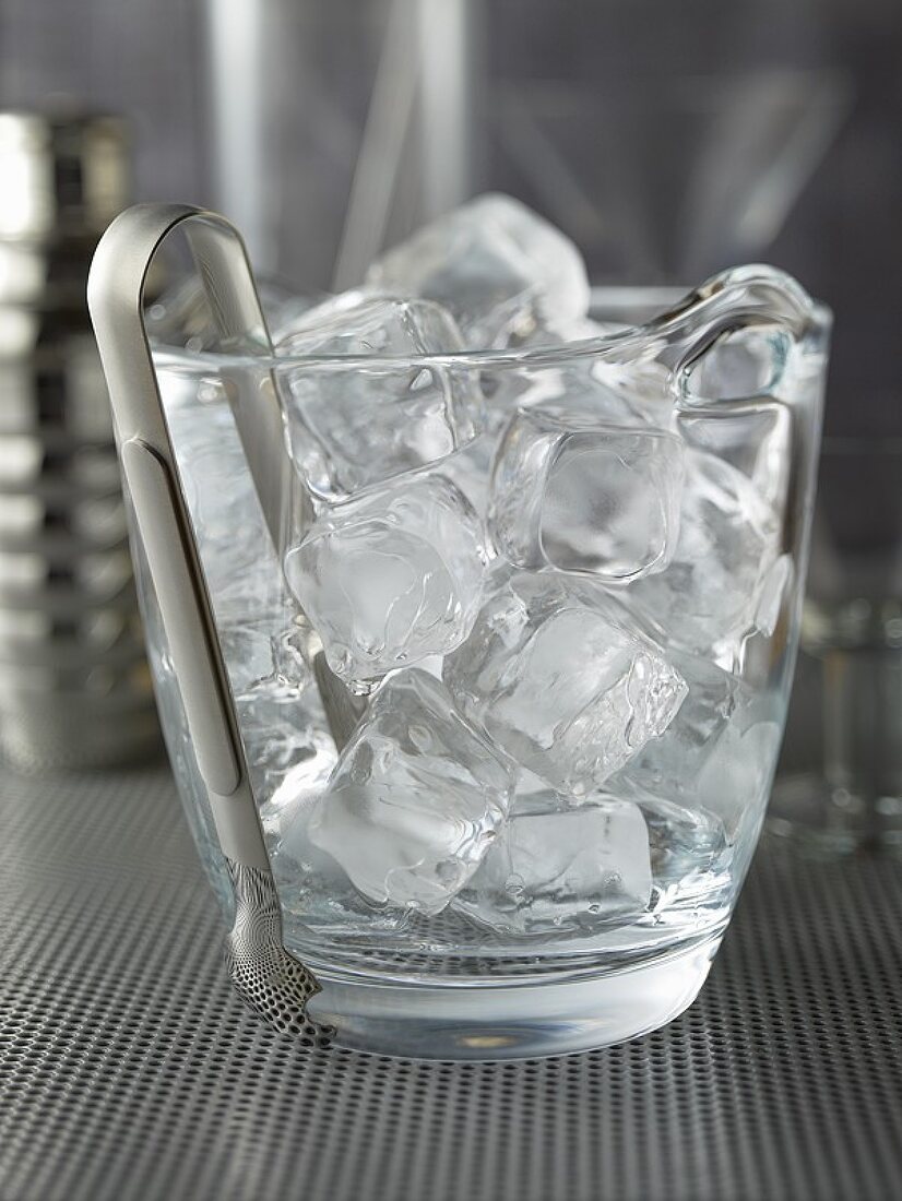 https://media01.stockfood.com/largepreviews/MjEwOTkyODI=/00680622-Ice-cubes-and-ice-tongs-in-a-glass-container.jpg