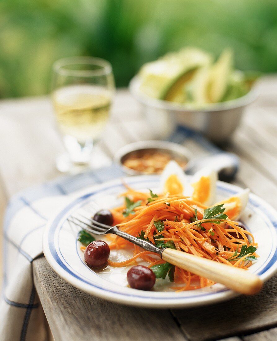 Möhrensalat mit Oliven auf rustikalem Tisch im Freien