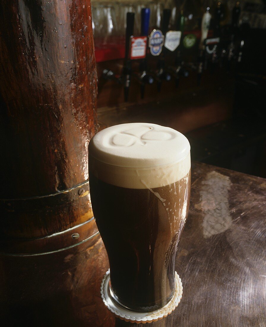 Glass of Dark Beer with Foam on a Bar