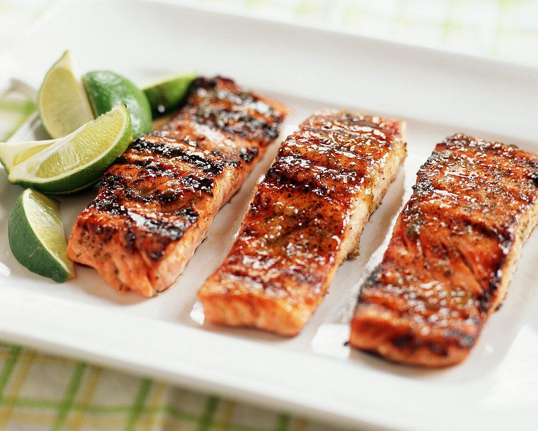Three Fillets of Glazed Grilled Salmon on a Platter with Limes