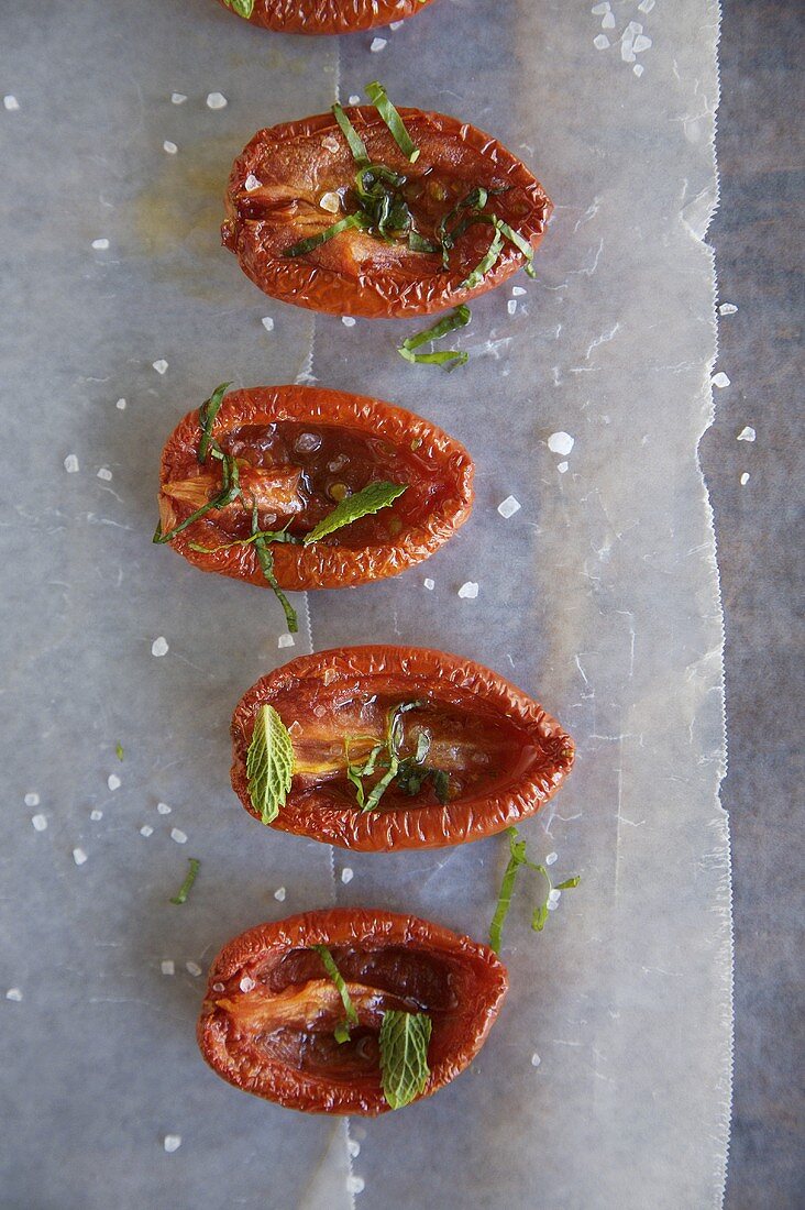 Getrocknete Tomaten mit Kräutern und Meersalz auf Backpapier