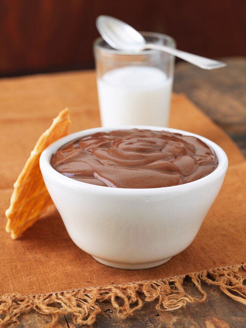 Eine Schüssel Schokopudding mit Waffel und einem Glas Milch