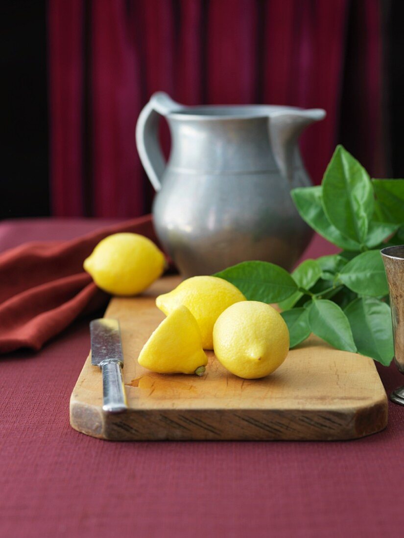 Fresh Lemons on a Cutting Board with a Knife; Pitcher
