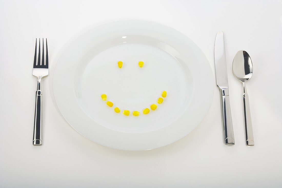 Corn Kernels Forming a Smiley Face on a White Dinner Plate