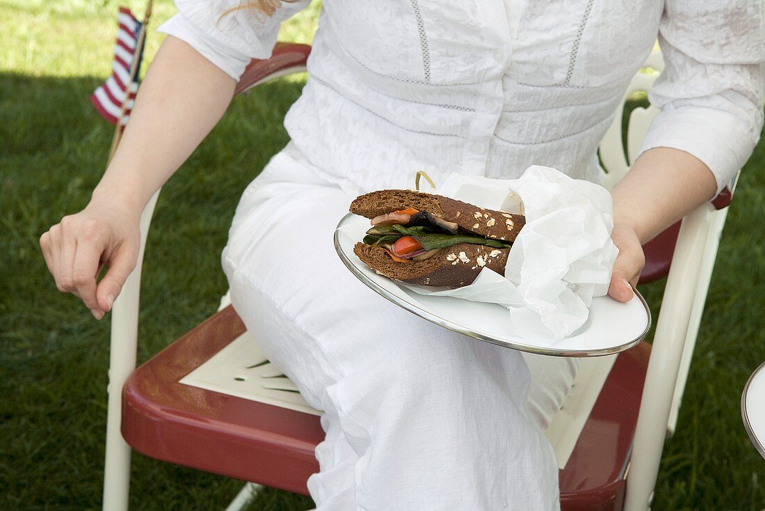 Frau hält Sandwich auf Teller am 4th of July (USA)